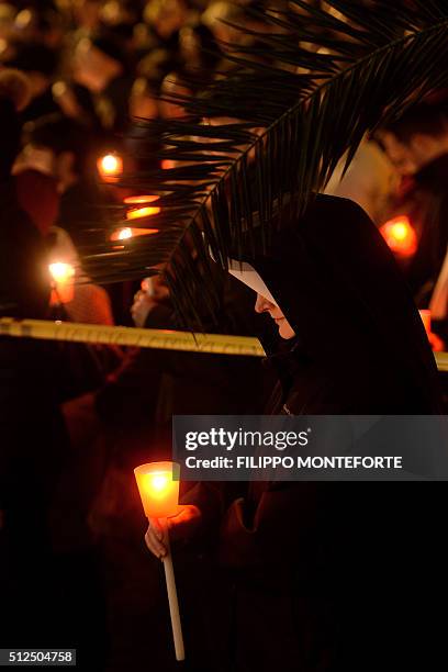 Nun holding a candle follows the way of the cross by Jesus Christ on Via della Conciliazione leading from St.Peter's Basilica at the Vaticano in Rome...