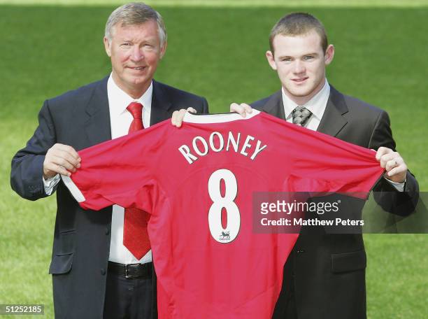 Sir Alex Ferguson poses with Wayne Rooney of Mancester United and a Manchester United shirt after the press conference to unveil Manchester United's...
