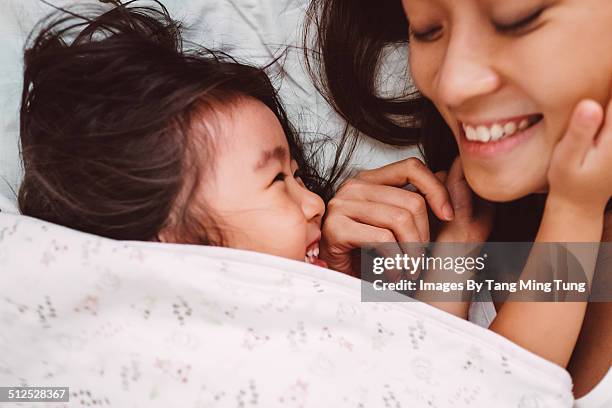 mom & child playing joyfully on bed - mom head in hands stock pictures, royalty-free photos & images