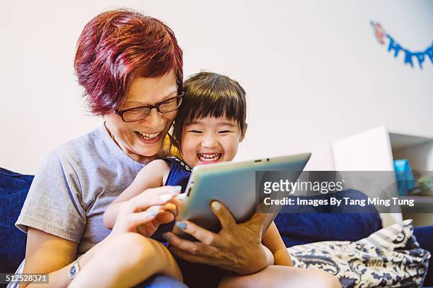 Child playing tablet with her grandma joyfully