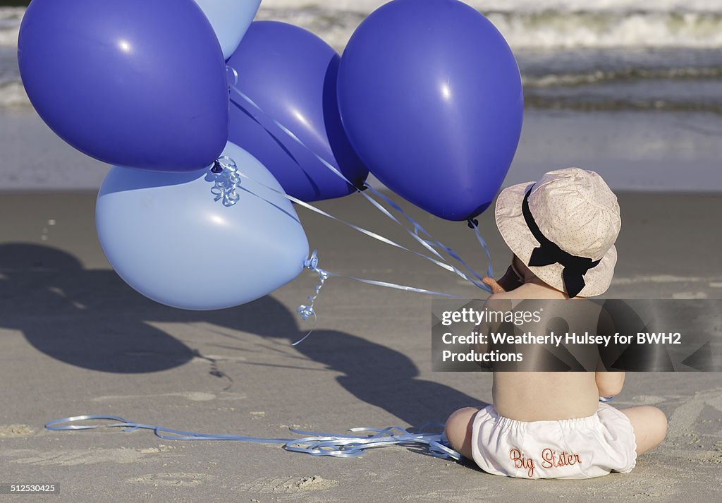Baby sister with blue balloons