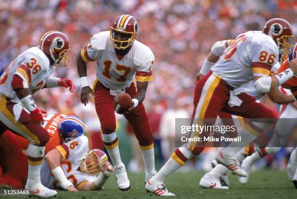 Quarterback Doug Williams of the Washington Redskins prepares to hand of the ball to running back Timmy Smith during Super Bowl XXII against the...