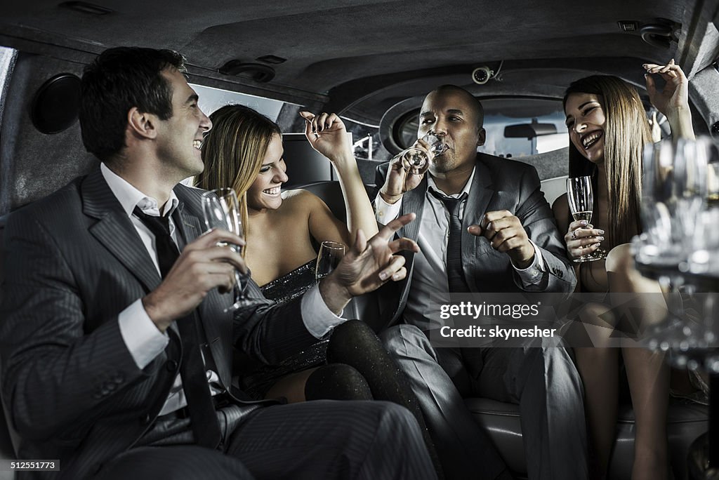 Cheerful businessmen with young women in a limousine.