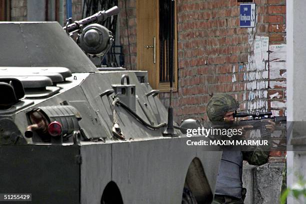 Russian special forces soldier aims at a position outside the school, where a group of gunmen, wearing belts laden with explosives, are holding...