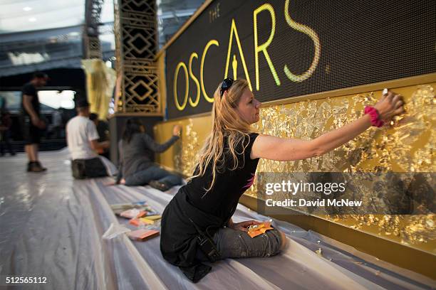 Scenic artist Dena D'Angelo applies imitation gold leaf to a wall in the red carpet arrivals area outside the Dolby Theatre as preparations continue...