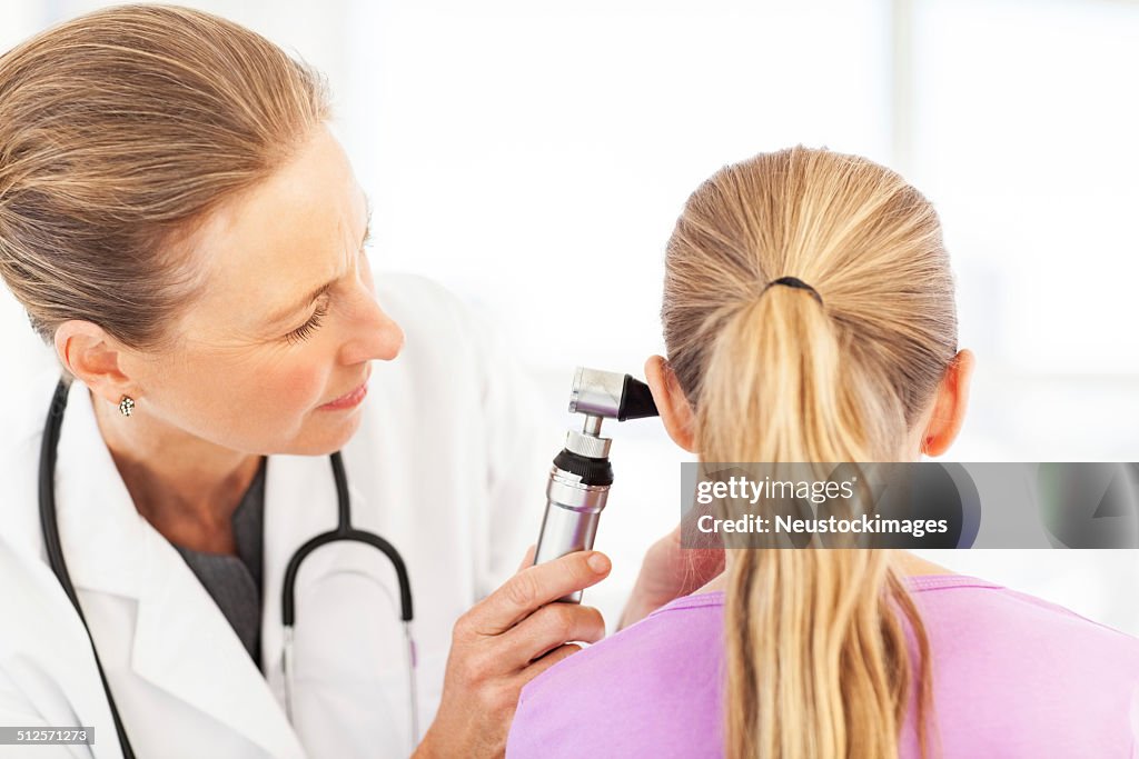 Female Doctor Examining Girl's Ear With Otoscope