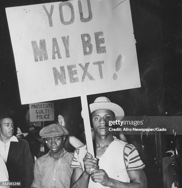 African-American protesters holding signs reading 'You May Be Next' and marching in a protest against police brutality after the shooting death of an...