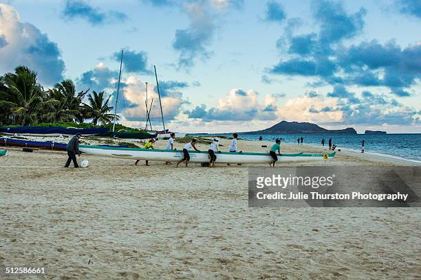 Paddlers Carry Their Canoe in From the Water During Sunset at the Vacation Travel Destination Lanikai Beach, Hawaii on the Island of Oahu. The Mokapu...