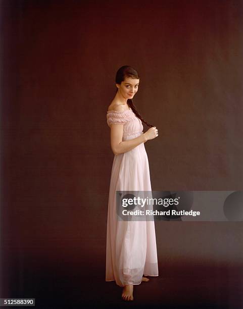 Boudoir Gifts to Make a Lady Lovelier: Full shot of a model wearing a pink nylon tricot and net Empire-style night gown; dark brown, old master-look...