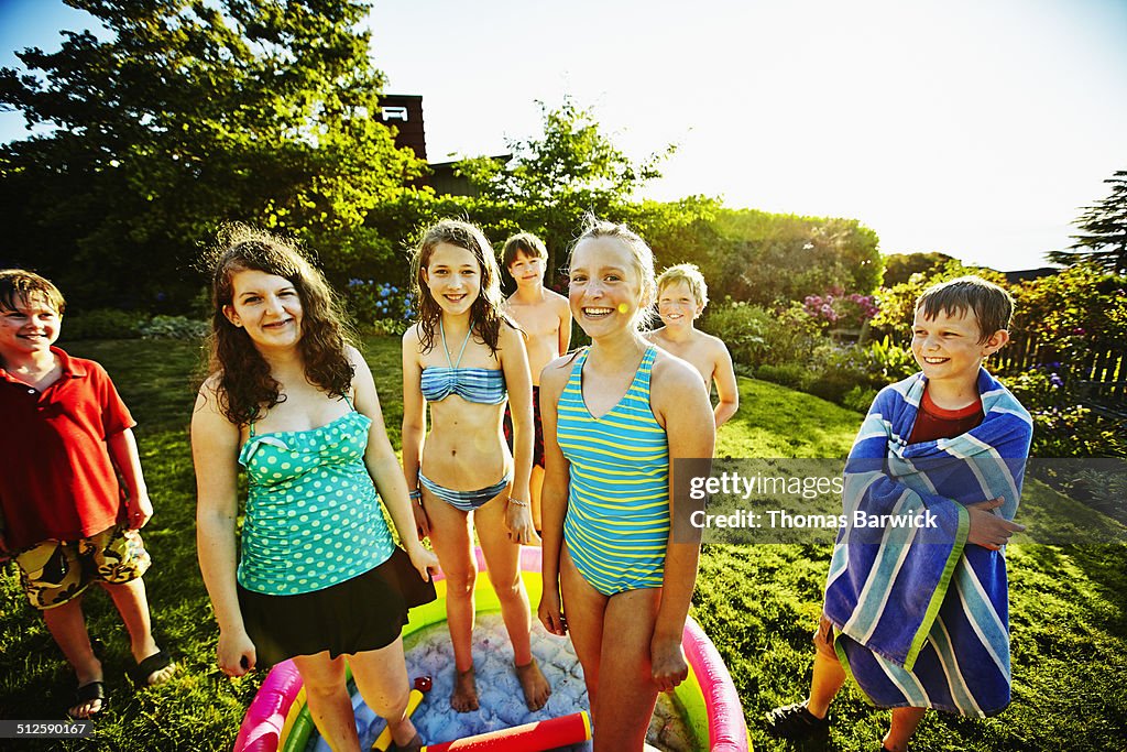 Smiling group of kids in swimsuits in backyard