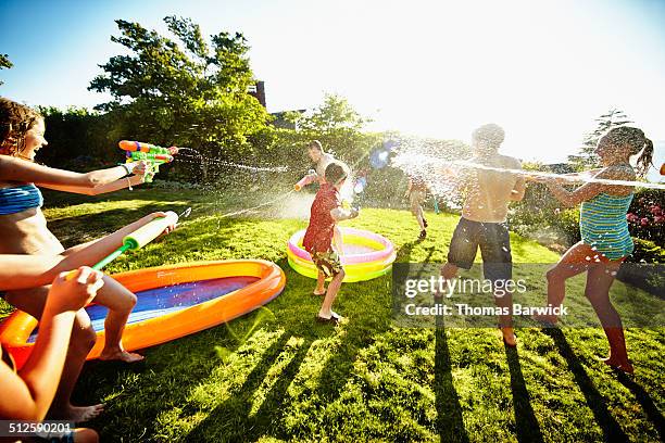 group of young kids having water fight against dad - pistola de agua fotografías e imágenes de stock