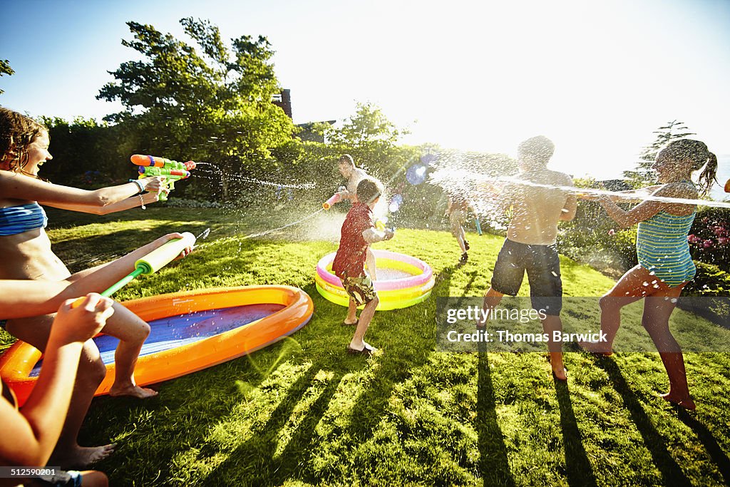 Group of young kids having water fight against dad
