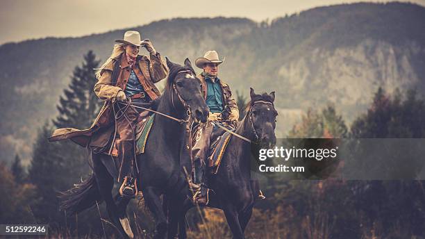 cowboy and cowgirl riding on horses through the woods - horse blanket stockfoto's en -beelden