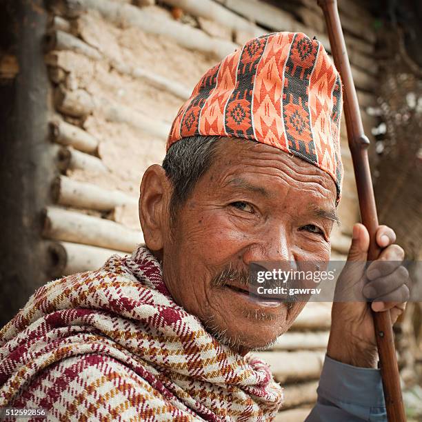 outdoor image of senior nepalese peasant man holding a stick. - nepal portrait stock pictures, royalty-free photos & images