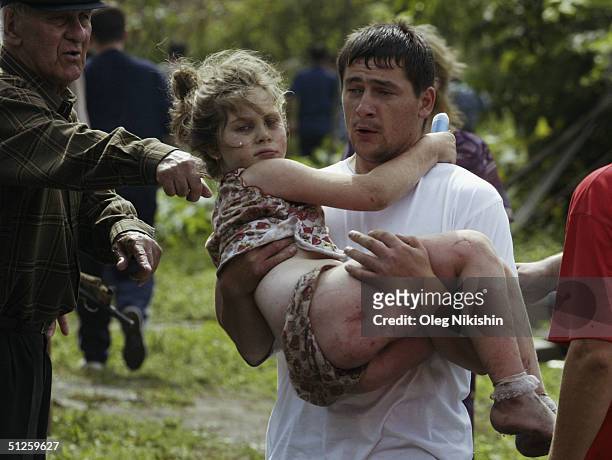 Volunteer carries an injured girl after special forces stormed a school seized by Chechen separatists on September 3, 2004 in the town of Beslan,...