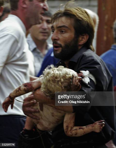 Volunteer carries an injured child after special forces stormed a school seized by Chechen separatists on September 3, 2004 in the town of Beslan,...