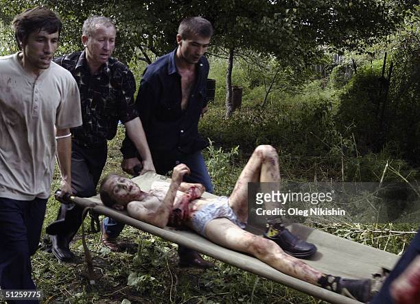 Volunteers carry an injured boy after special forces stormed a school seized by Chechen separatists on September 3, 2004 in the town of Beslan,...
