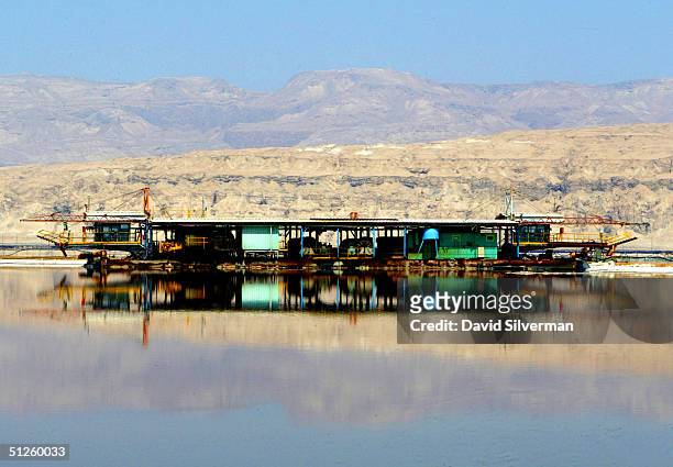 Carnalite-dredgging barge floats on the mirror-like surface of a Dead Sea Works evaporation pool at the industrial giant's potash recovery plant on...