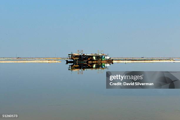 Carnalite-dredgging barge floats on the mirror-like surface of a Dead Sea Works evaporation pool at the industrial giant's potash recovery plant on...