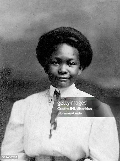 Half length portrait of African American woman wearing white collared top with ribbon tie, short hairdo, neutral facial expression, Lebanon,...