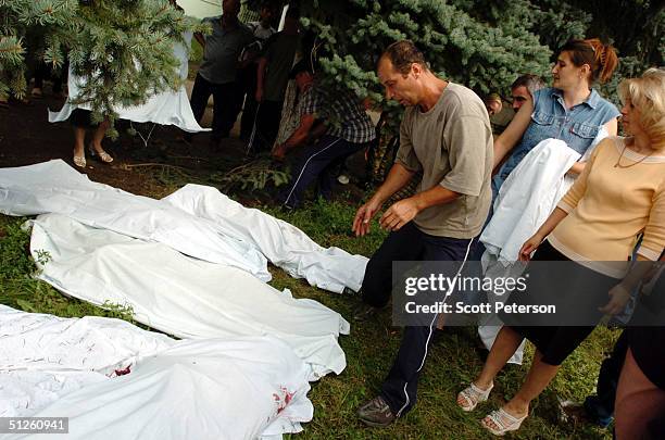 Russian man stands over bodies covered with sheets near a school September 3, 2004 in Beslan, Russia. More than 200 people were reportedly killed and...