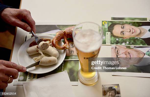 Supporter eats Bavarian veal sausage and drinks a beer while he waits for Winfried Kretschmann, Governor of Baden-Wuerttemberg and member of the...