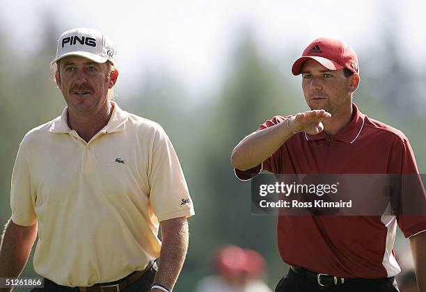 Miguel Angel Jimenez and Sergio Garcia of Spain walk down the par four 18th hole during the third round of the Omega European Masters at...