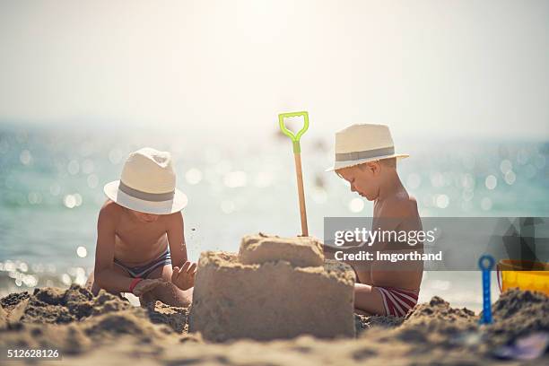 two brothers building a sandcastle on beautiful beach - beach boys stock pictures, royalty-free photos & images