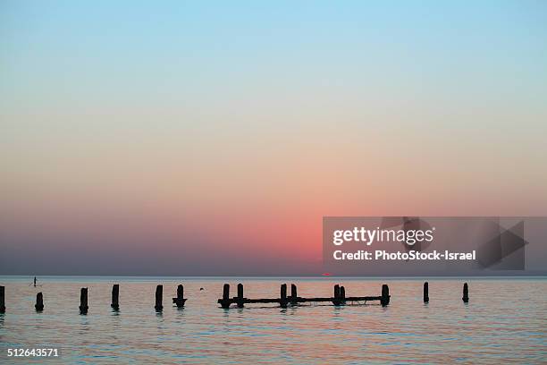 remains of a wharf at sunset - drab colored stock pictures, royalty-free photos & images