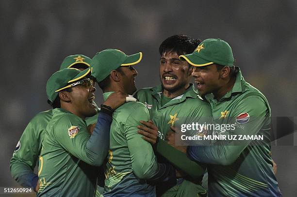 Pakistan cricketer Mohammad Amir celebrates with teammates after the dismissal of Indian cricketer Suresh Raina during the match between India and...