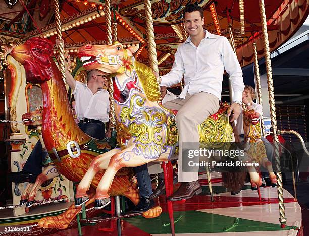 Bachelor Boy James Getzlaff gets a ride on a merry-go-round at a media call during his visit looking for Mr Right for the new reality show "Boy Meets...