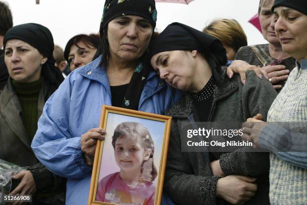 Family and friends of those killed in the school hostage crisis cry during a mass funeral in the rain September 6, 2004 in Beslan, southern Russia....