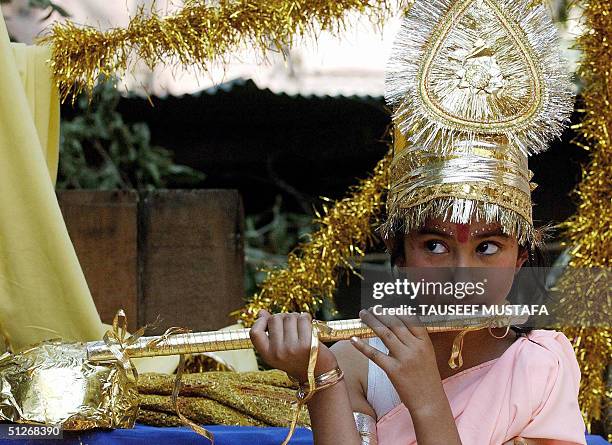 Kashmiri Pandith girl, posing as Hindu God Lord Krishna, plays flute as she sits at the top of a vehicle during a procession in Srinagar, 07...