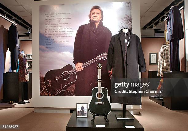 Martin guitar and a poster of him wearing the coat and holding the guitar along with other memorabilia belonging to country singing legends Johnny...