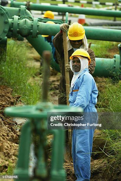 Workers maintain pipes at oil and gas processing facilities at Seria, September 7, 2004 in Brunei. Brunei produces around 218,000 barrels a day of...