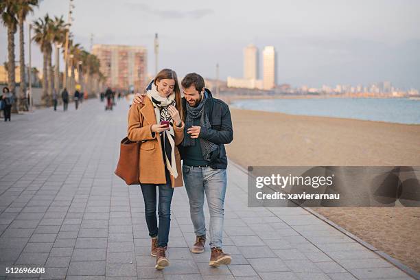 paar teilen eine nachricht auf intelligente telefon - winter barcelona stock-fotos und bilder