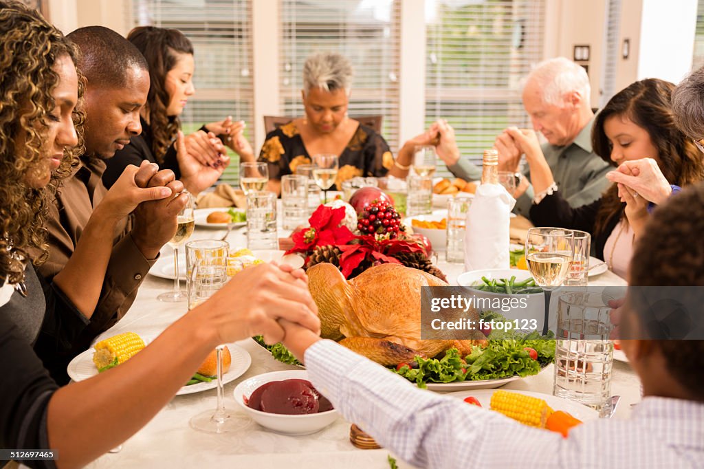 Christmas:  Family prays before eating holiday dinner.