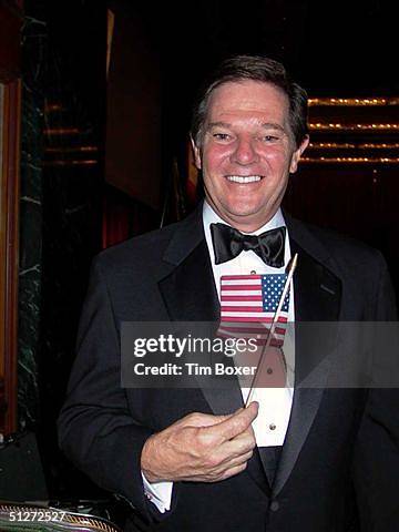 United States House of Representatives majority leader Tom DeLay holds an American flag while wearing a tuxedo, New York City, early 2000s.