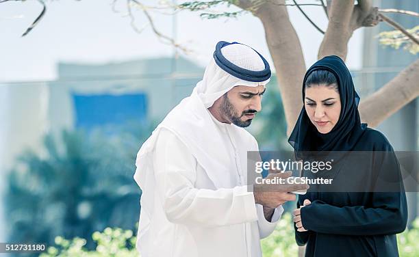 arab man showing smartphone to an arab woman - angry couple arab stock pictures, royalty-free photos & images