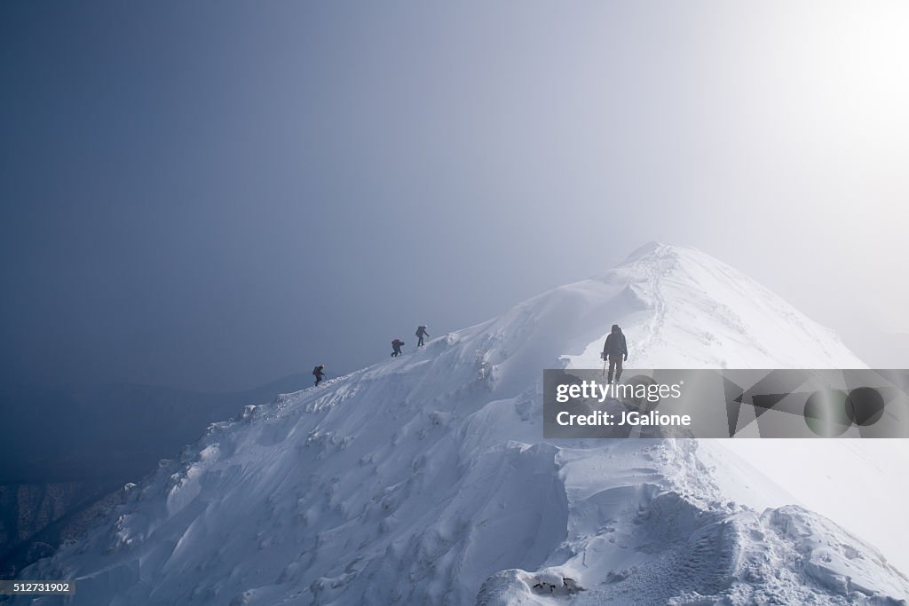 Four ice climbers scaling a mountains summit