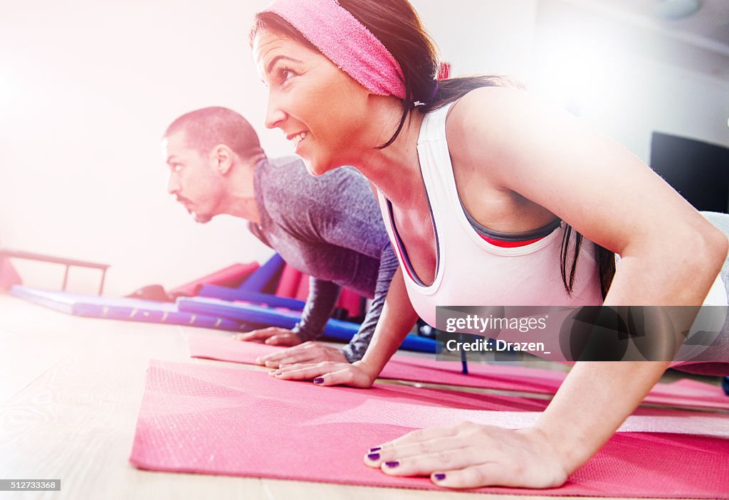 Two young athletes warming up and exercising push-ups in gym