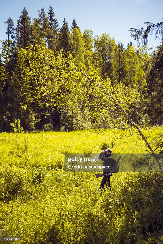 Hunter Observing a Green Field Through Binoculars