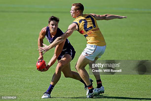 Ethan Hughes of the Dockers handballs under pressure from Tom Lynch of the Crowsduring the 2016 AFL NAB Challenge match between the Fremantle Dockers...
