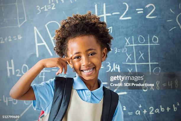 smart kindergarten private school student pointing at head confidently - african american school uniform stock pictures, royalty-free photos & images