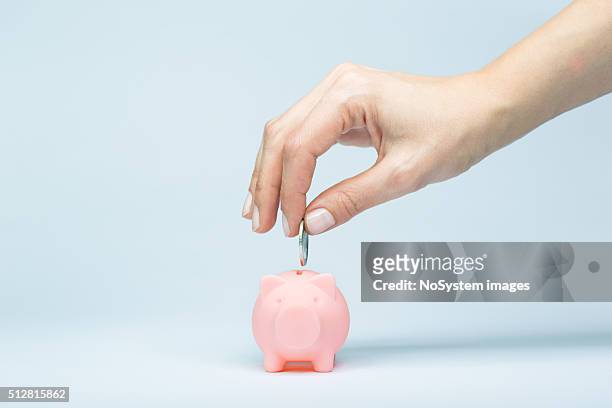 mujer mano poner monedas en una alcancía - money box fotografías e imágenes de stock