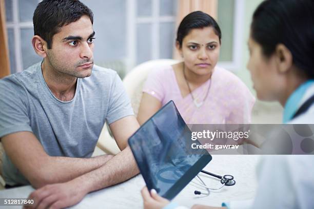 young female doctor counseling patient on her desk. - married doctors stock pictures, royalty-free photos & images