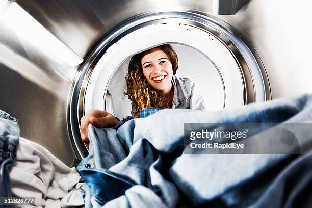 smiling blonde beauty loads her tumble dryer: seens from inside - wasserette stockfoto's en -beelden