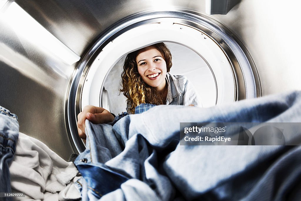 Smiling blonde beauty loads her tumble dryer: seens from inside