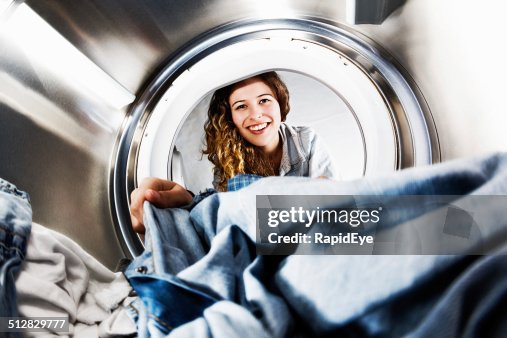 Smiling blonde beauty loads her tumble dryer: seens from inside Smiling blonde beauty loads her tumble dryer: seens from inside