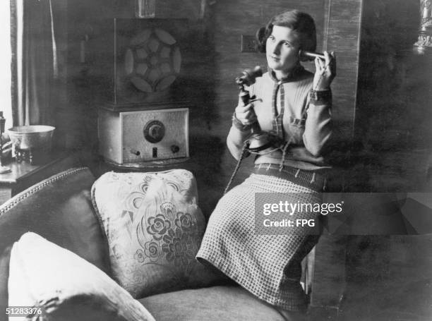 Young woman using a candlestick phone, circa 1920.